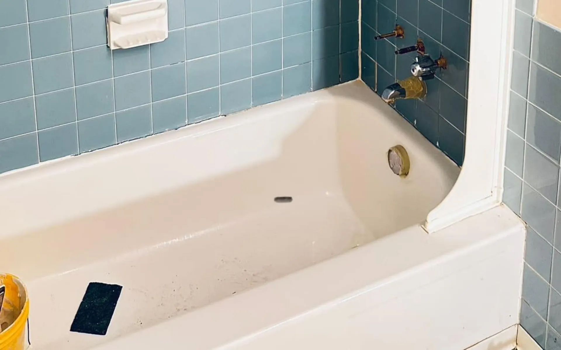 White bathtub with blue tile surround; soap dish and faucet visible.