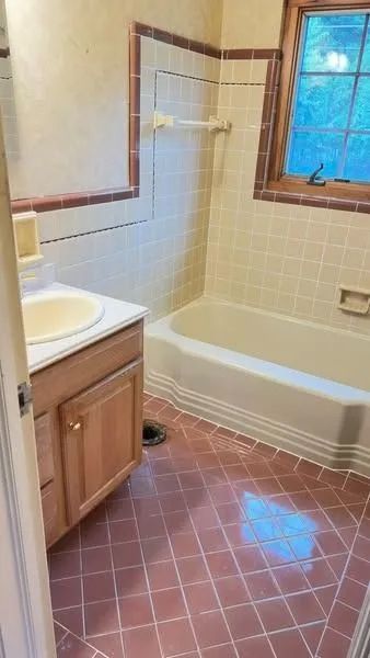Bathroom with pink tile floor, light yellow tile walls, and a wooden vanity.