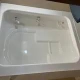 White built-in bathtub with rounded end, jets, and built-in seat.