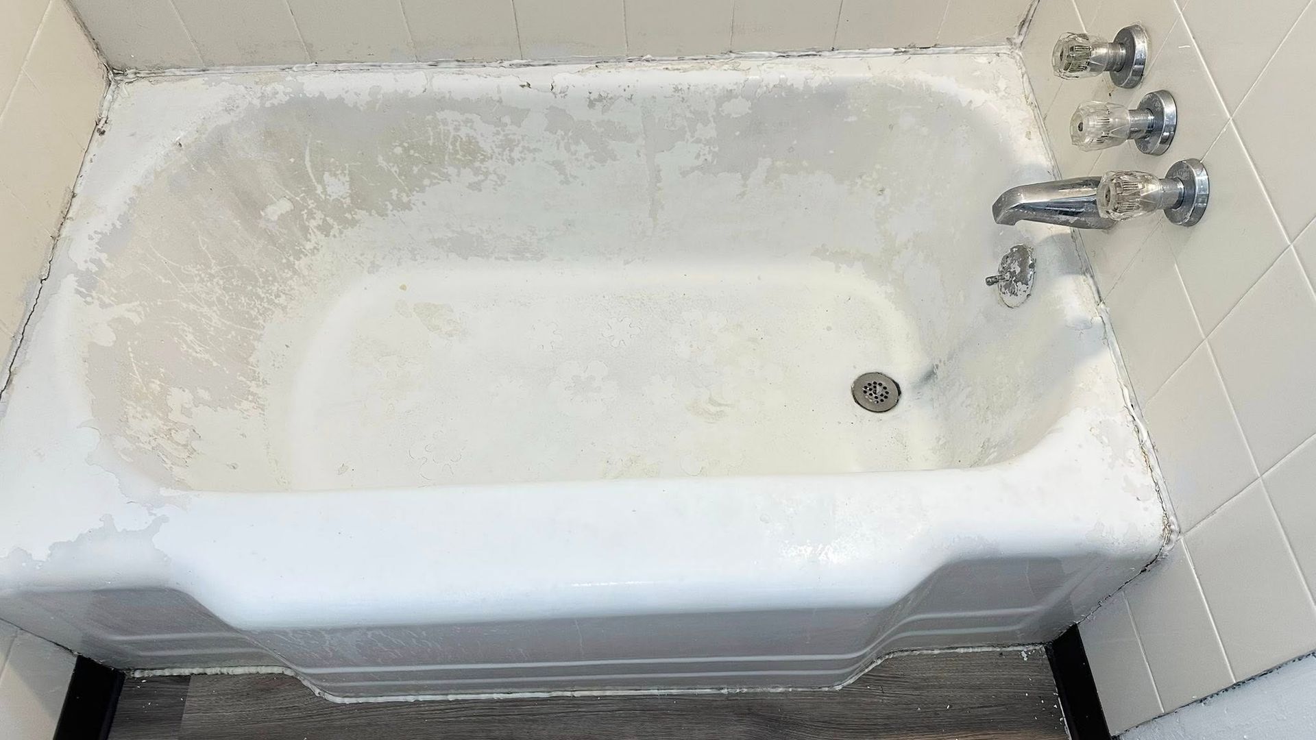 White bathtub with soap scum, in a tiled bathroom.