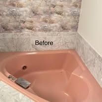 Pink jacuzzi tub with marble tile and floral wallpaper in a bathroom.