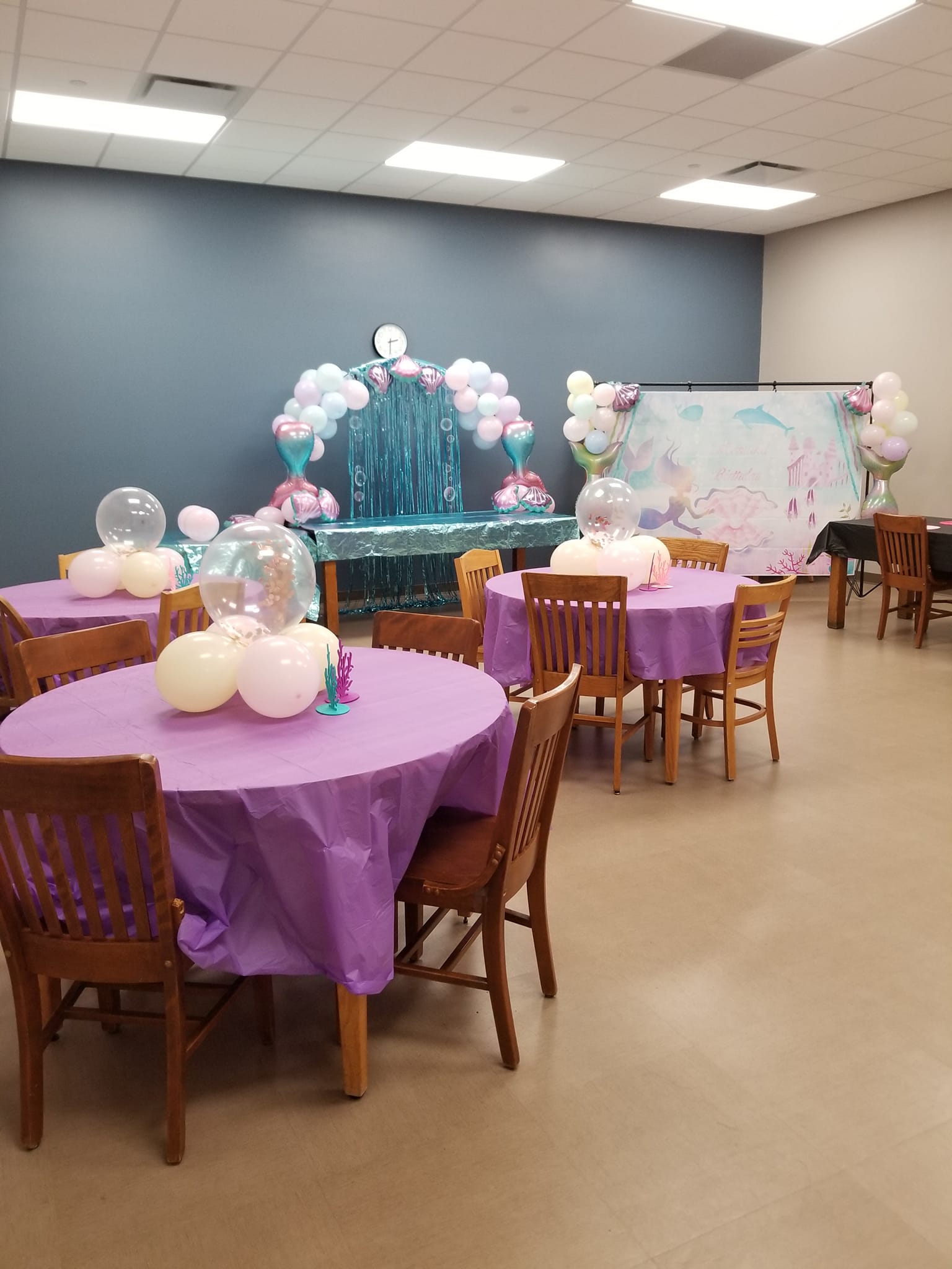 A room filled with tables and chairs decorated for a birthday party.