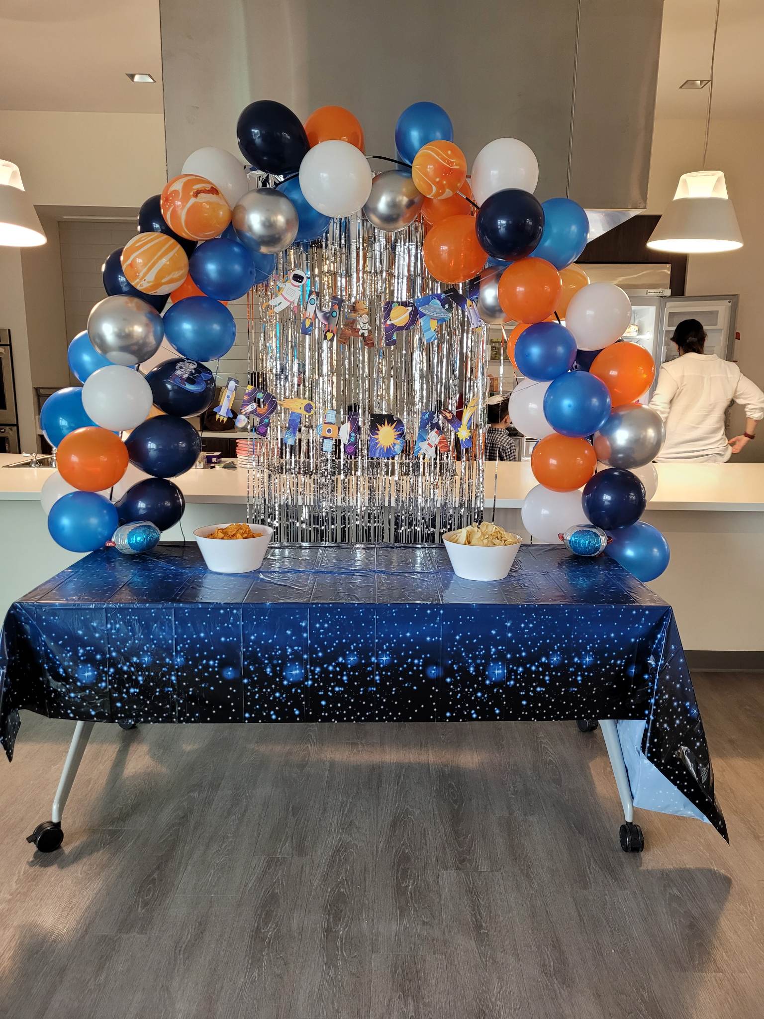 A table with a blue tablecloth and balloons on it.