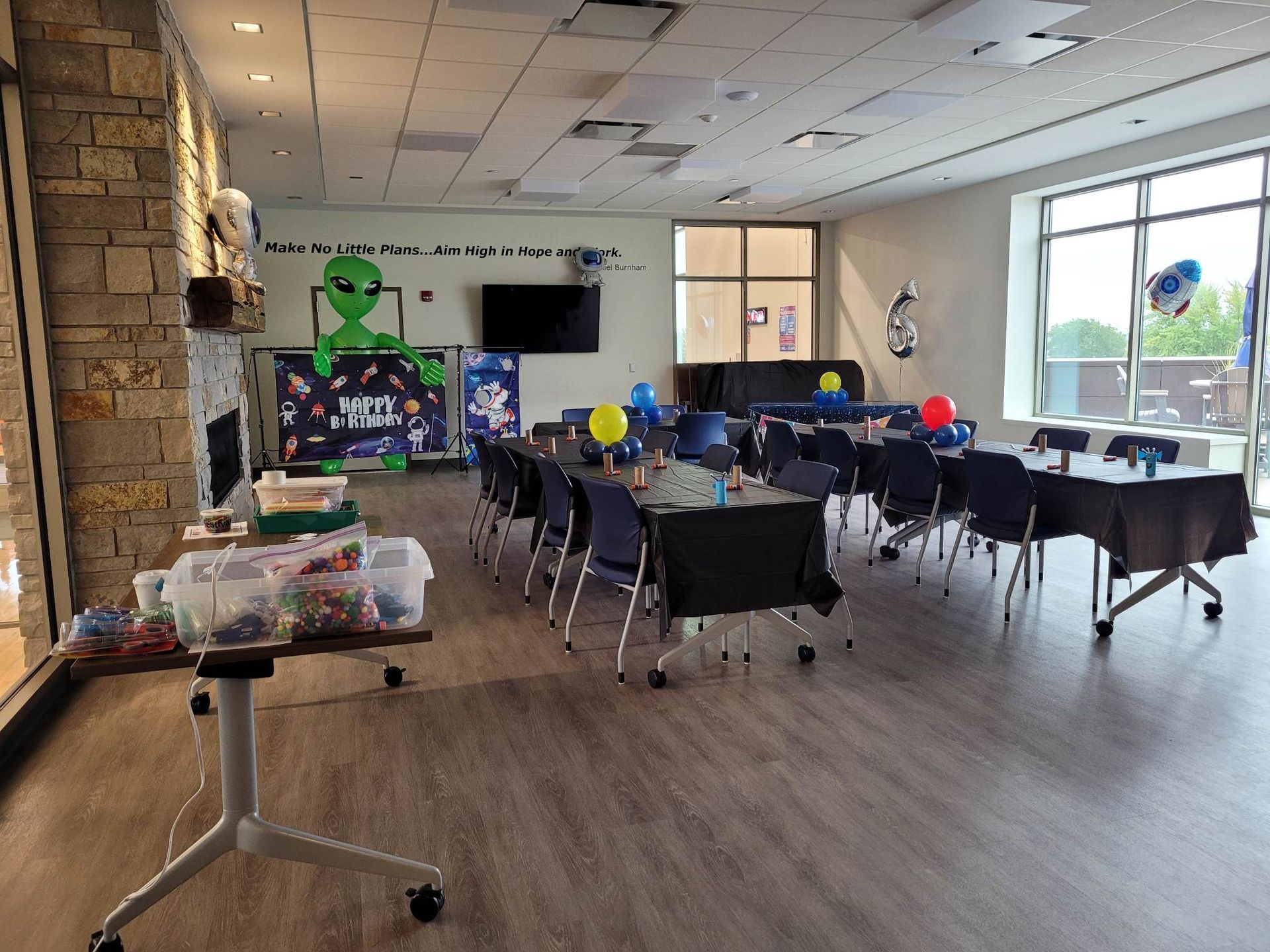 A large room filled with tables and chairs and balloons.