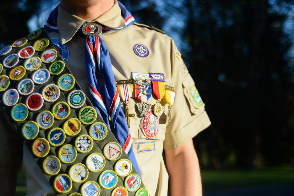 A boy scout with a lot of badges on his uniform