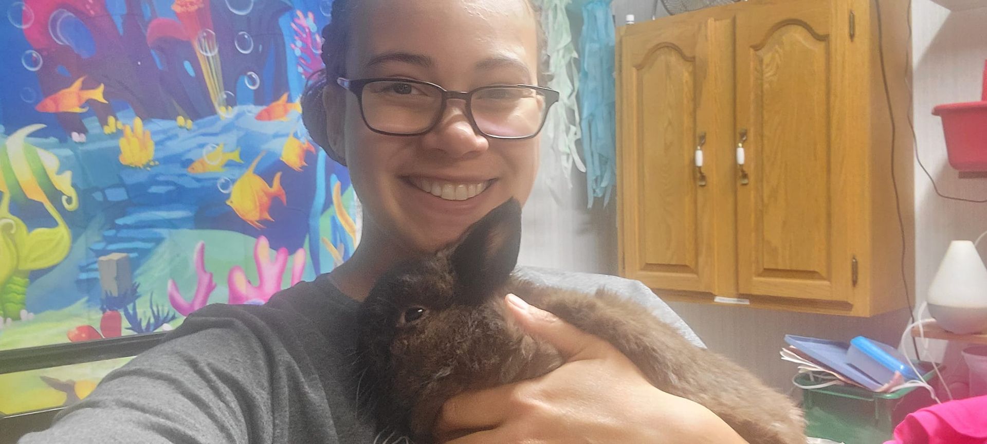 A woman wearing glasses is holding a cat in her arms.