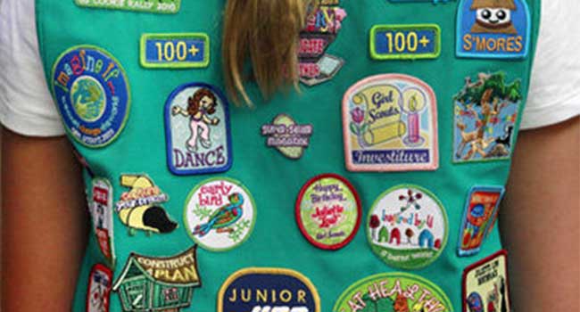 A girl scout with a lot of patches on her vest