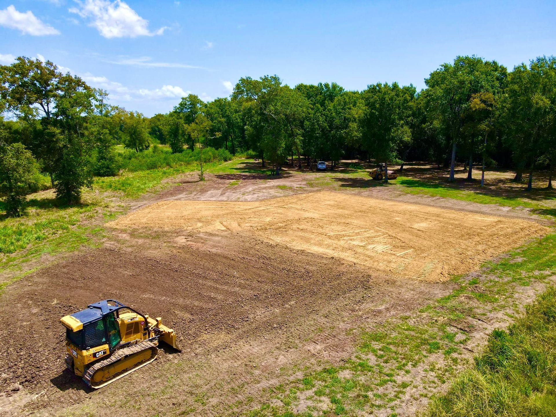 An aerial view of a bulldozer working on a dirt field.