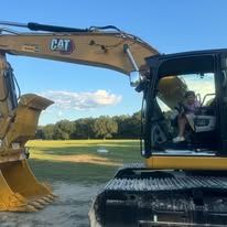 A little girl is sitting in the driver 's seat of a cat excavator.