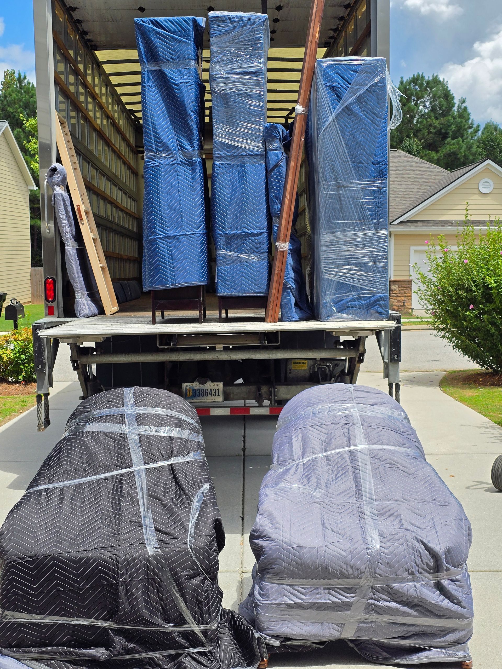 Moving truck loaded with furniture, including chairs, and upright pieces wrapped in protective covers.