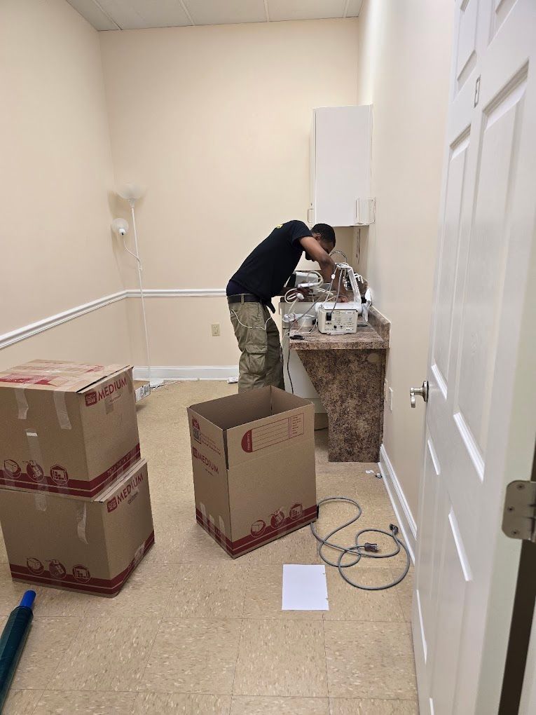A man is working on a sink in a room with boxes on the floor.