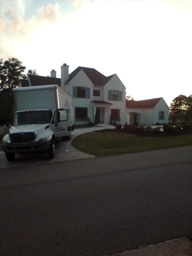 A white truck is parked in front of a large white house.