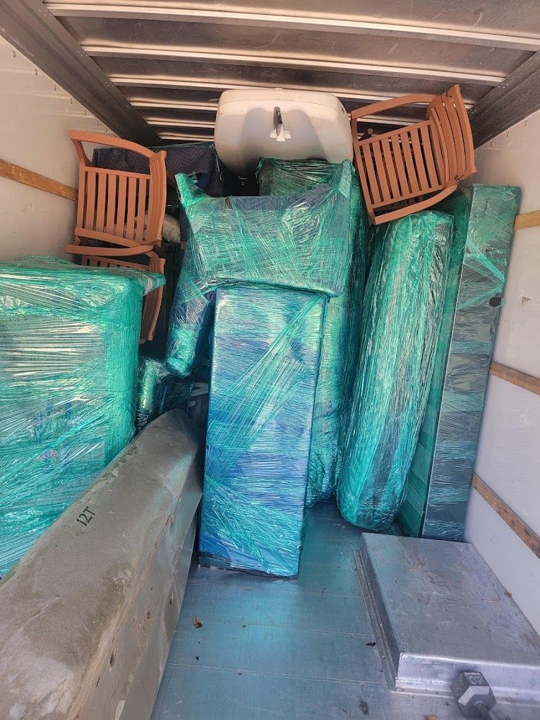 The inside of a moving truck filled with furniture wrapped in plastic.