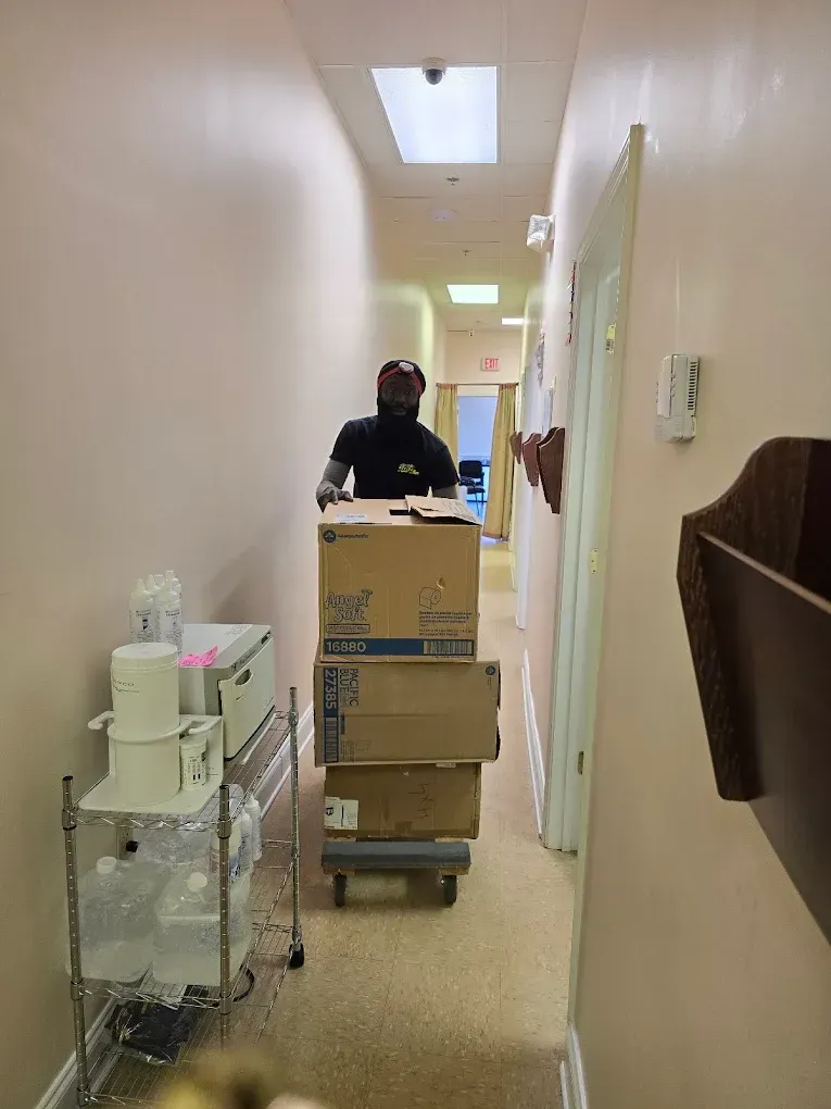 Person pushing a cart of boxes down a hallway.