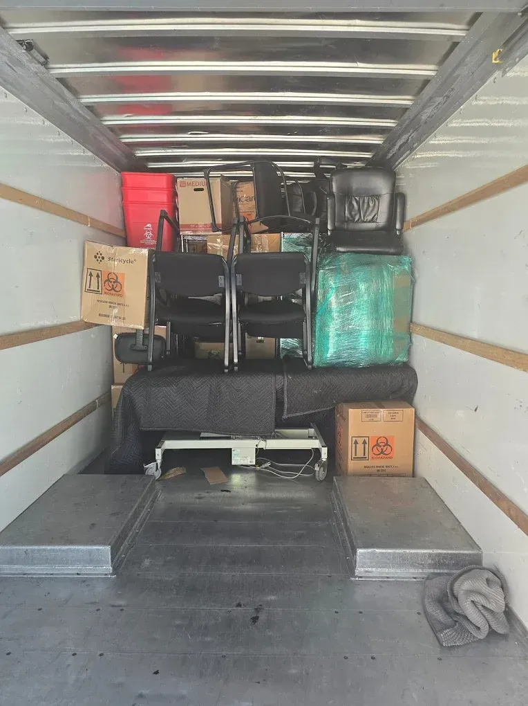 Inside a moving truck packed with furniture, boxes, and wrapped items.