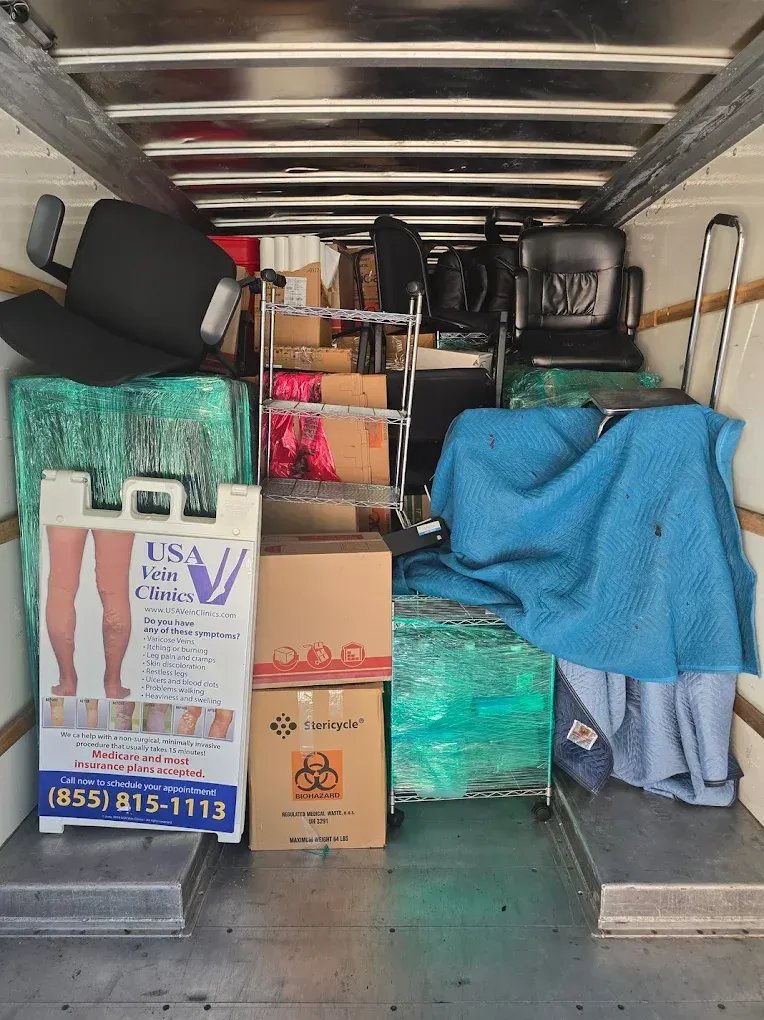 Interior of a moving truck packed with furniture, boxes, a medical sign, and wrapped items.