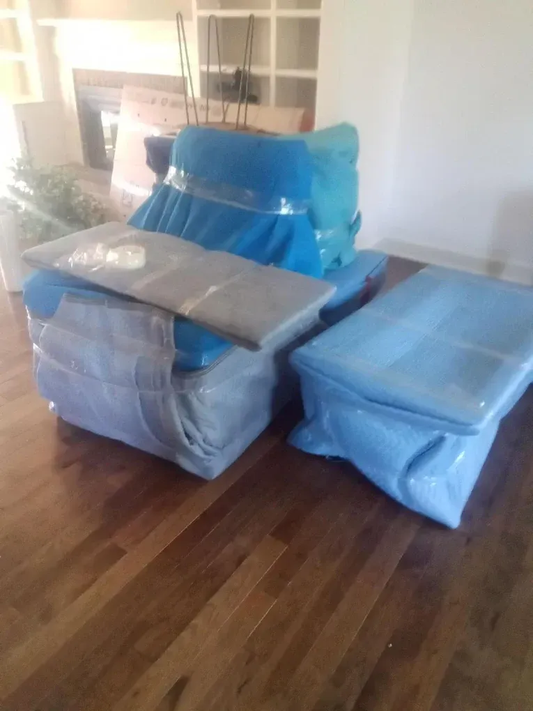 Furniture wrapped in blue and grey protective covers on a hardwood floor.