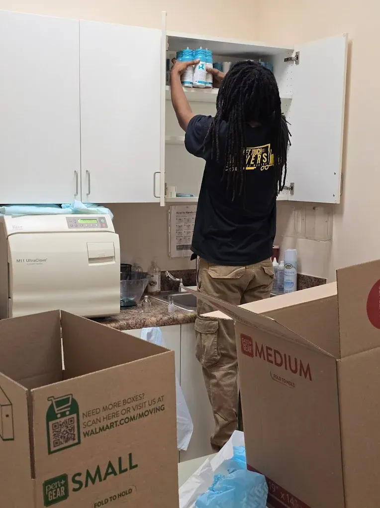 Person reaching into cabinet in a room with cardboard boxes.