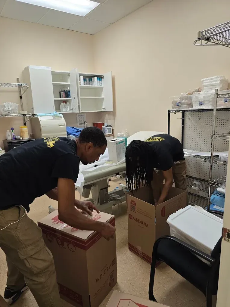Two people packing boxes in a medical office, possibly moving.