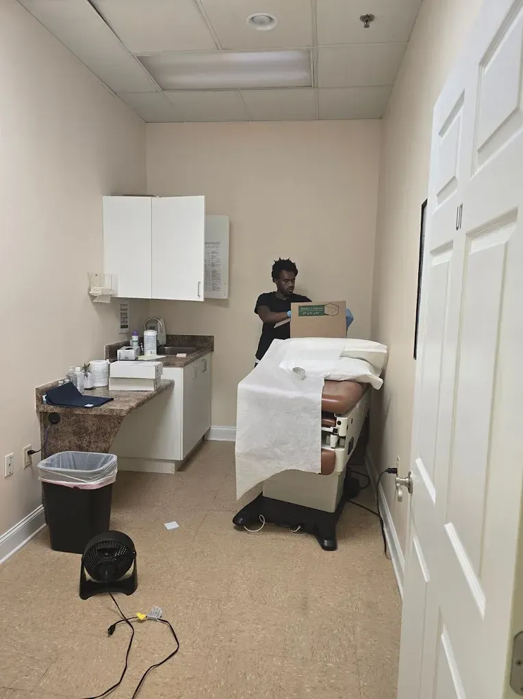 Examination room with medical table, cabinets, a person, and a fan.