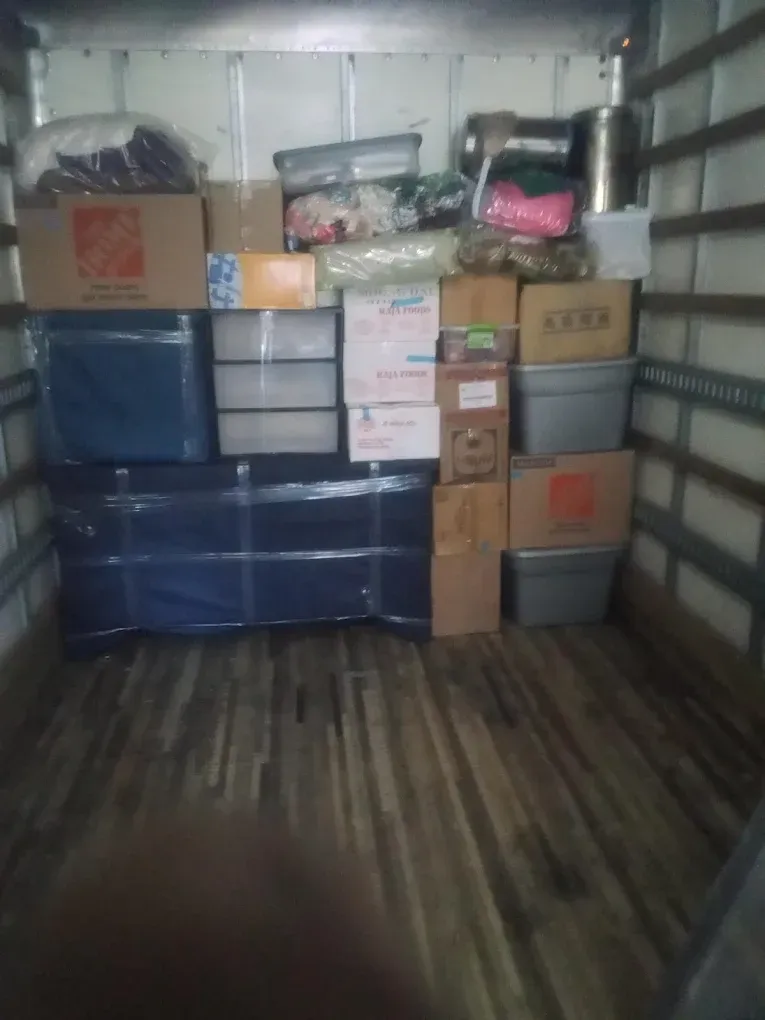 Boxes and furniture stacked inside a moving truck, ready to be transported.