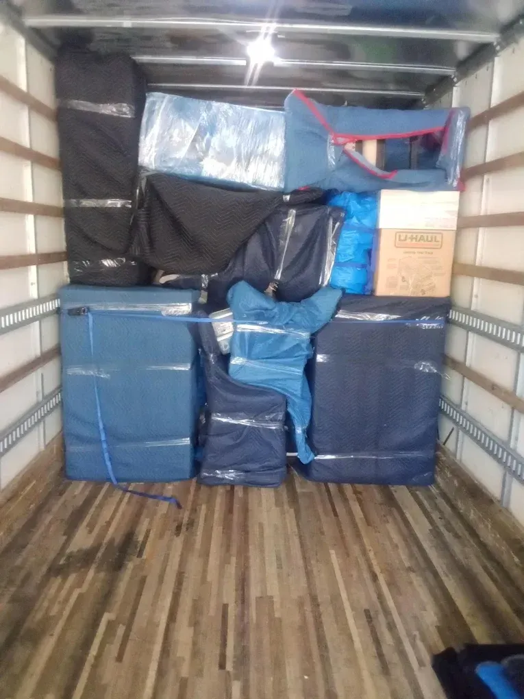 Boxes and furniture wrapped for moving, inside a truck.