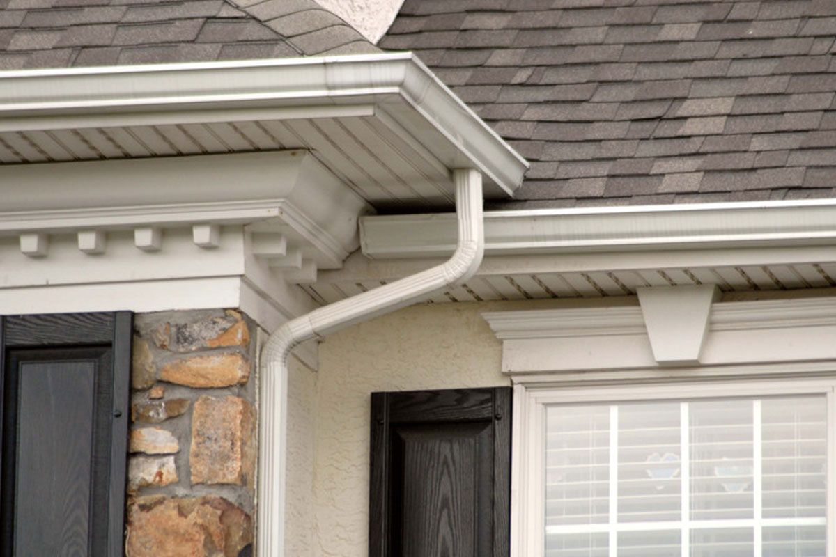 House exterior with white gutters, gray shingles, stone siding, and a window with white shutters