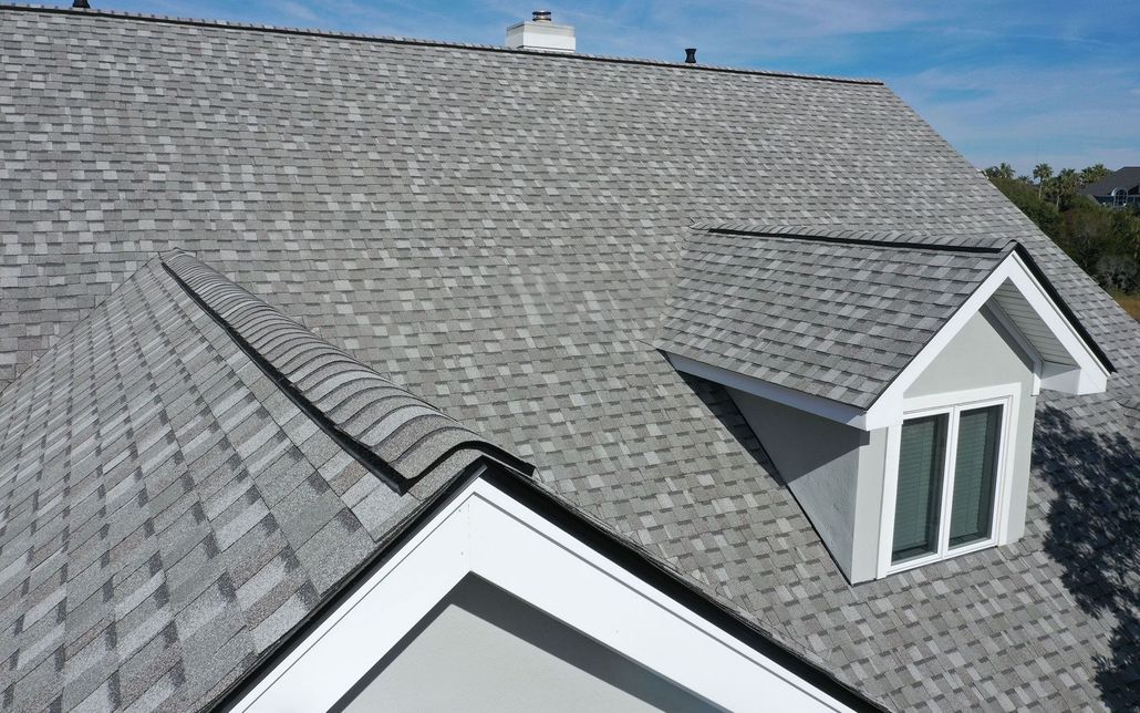 Gray shingle roof with dormer windows under a clear blue sky