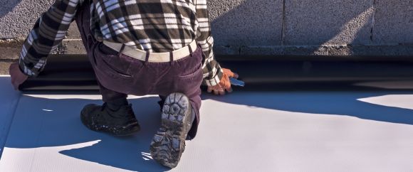 A man in a plaid shirt repairing a flat roof