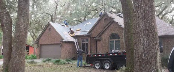 A couple of men are working on the roof of a house