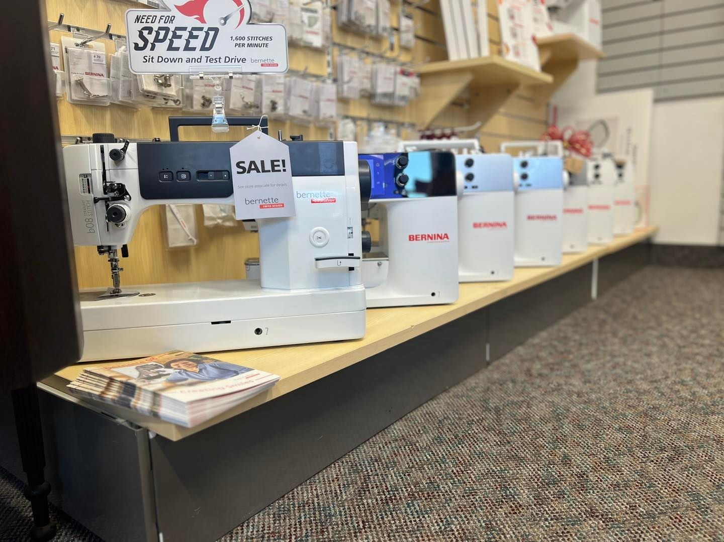 Row of sewing machines on display in a store, with sale signs
