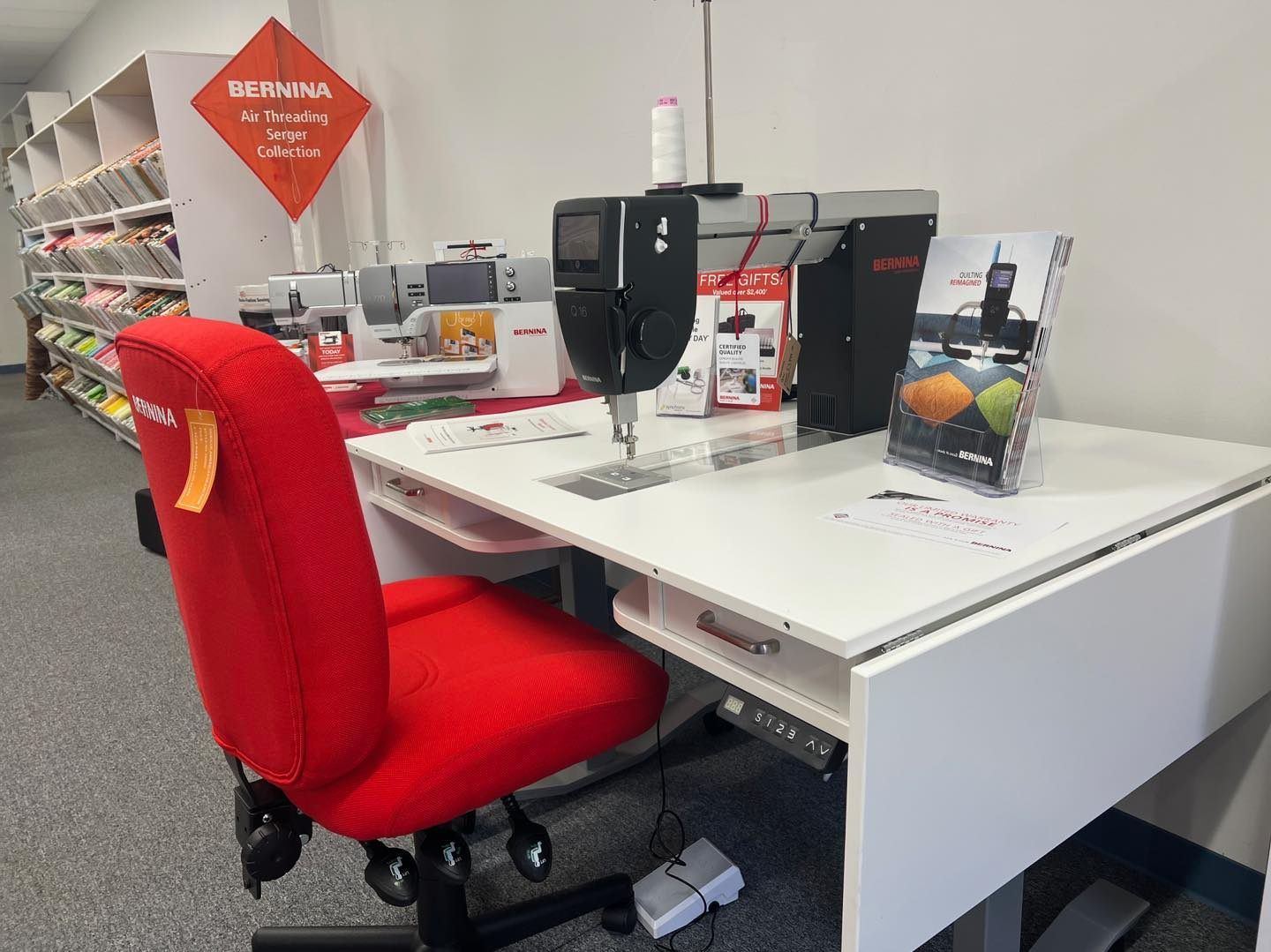 Red chair faces a white sewing table with a black sewing machine in a store