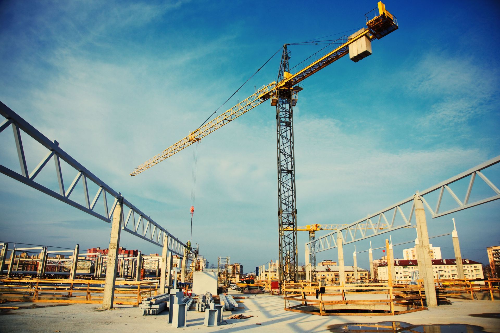 Construction site with a tall yellow crane and steel framework under a clear blue sky