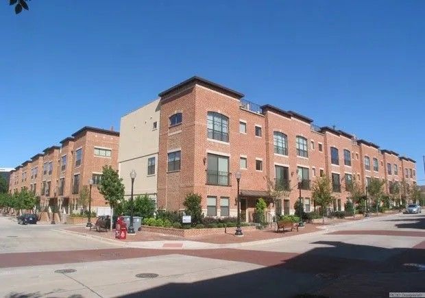 Brick townhouses on a sunny day. Buildings have multiple stories, with a brick facade and a blue sky overhead.