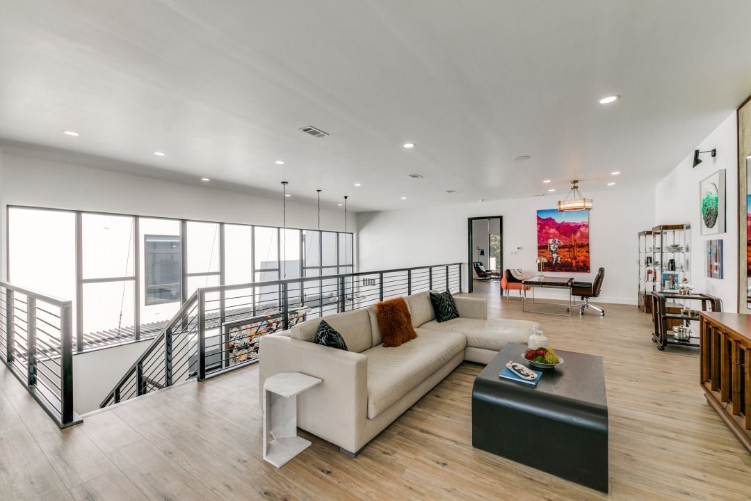 Spacious modern living room with a white sectional sofa, open-plan design, and a view to an office space.