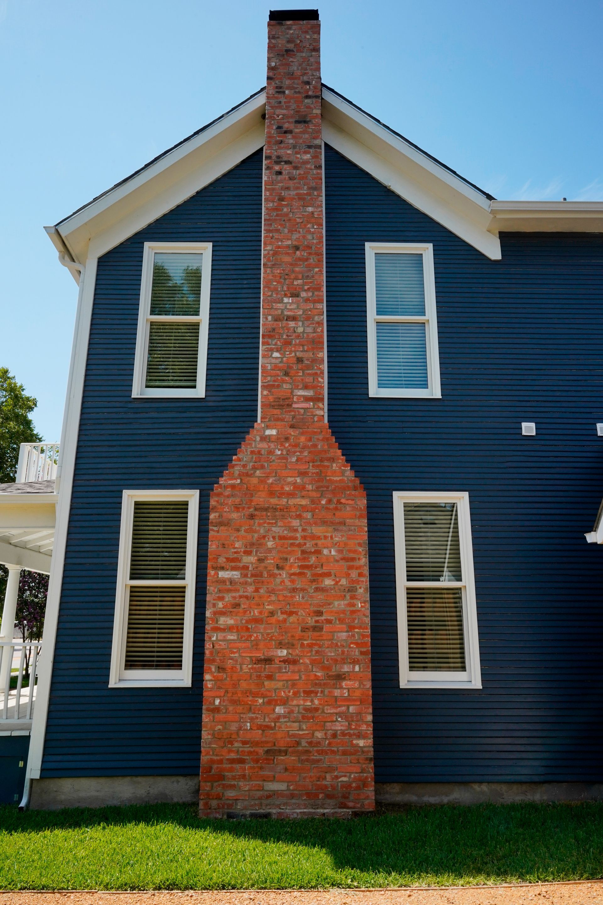 Blue house with a tall, red brick chimney centered against the back wall, with four windows.