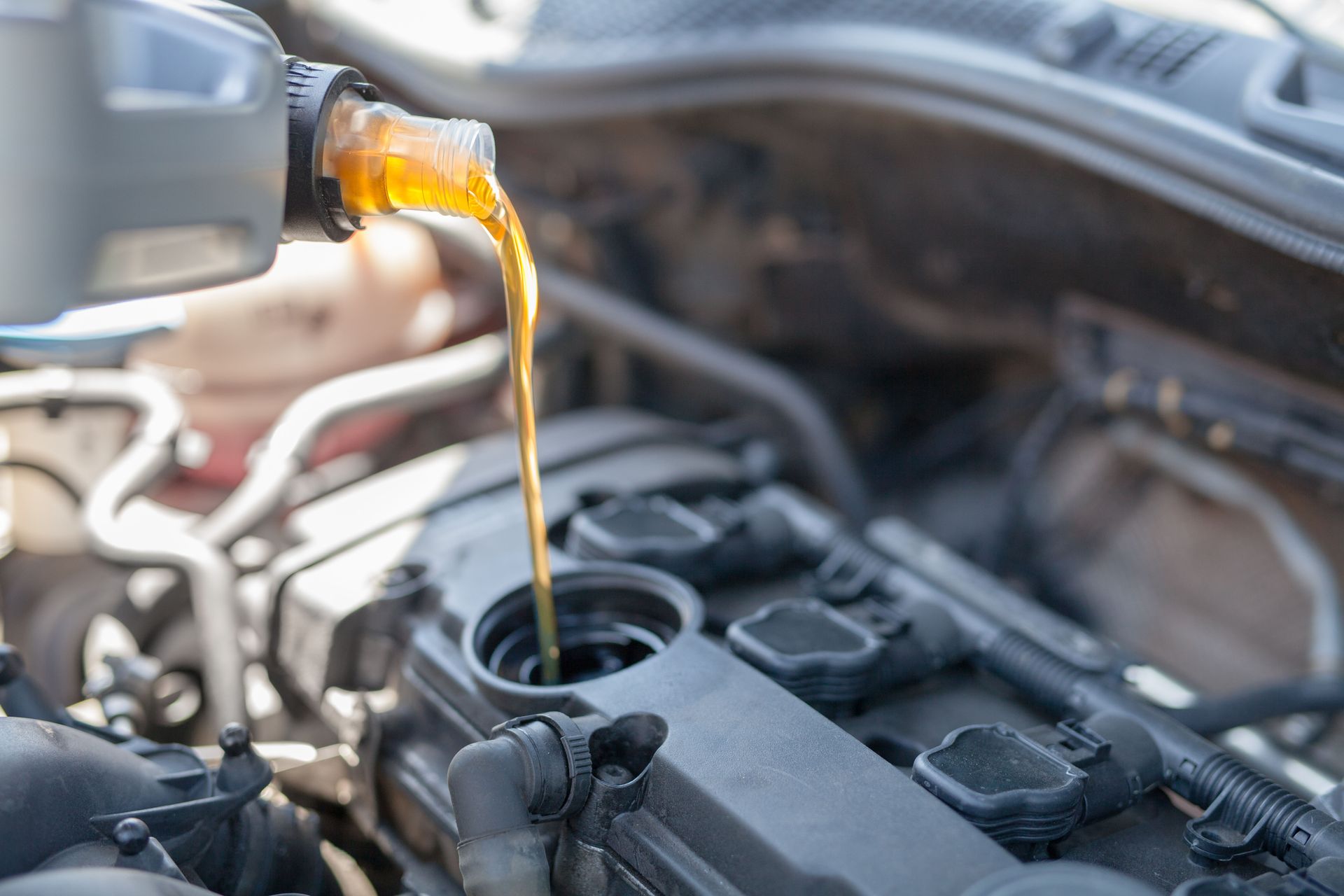 A person is pouring oil into a car engine.