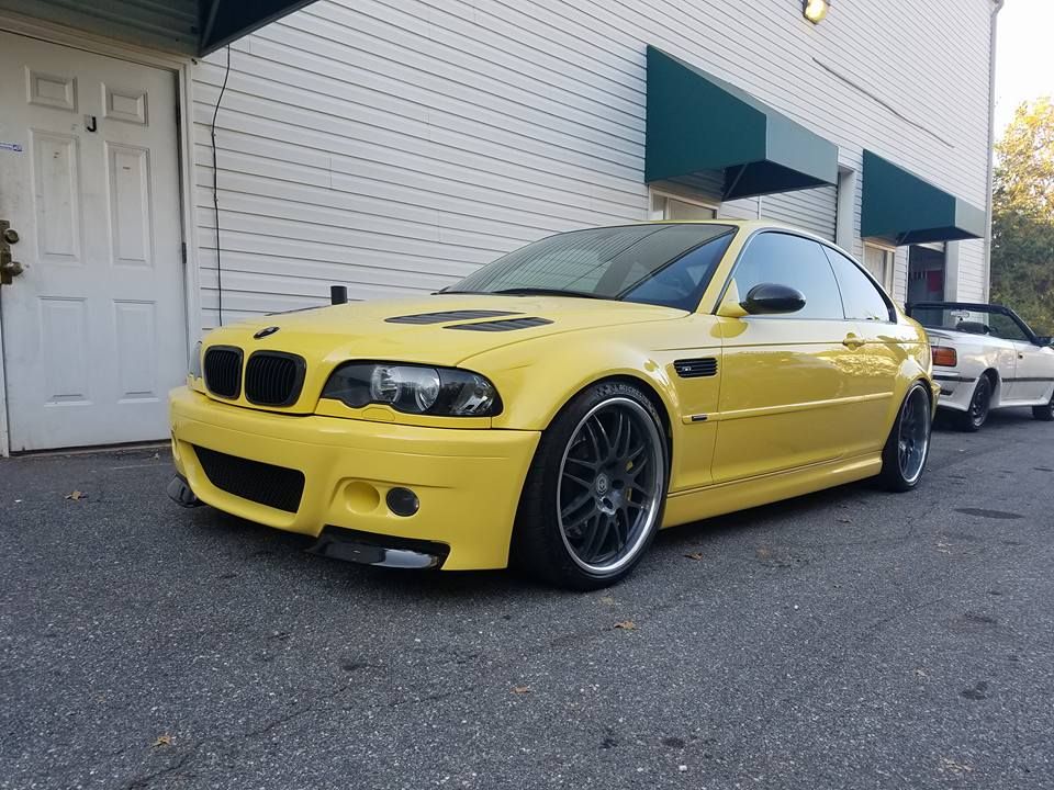 A yellow bmw is parked in front of a building.