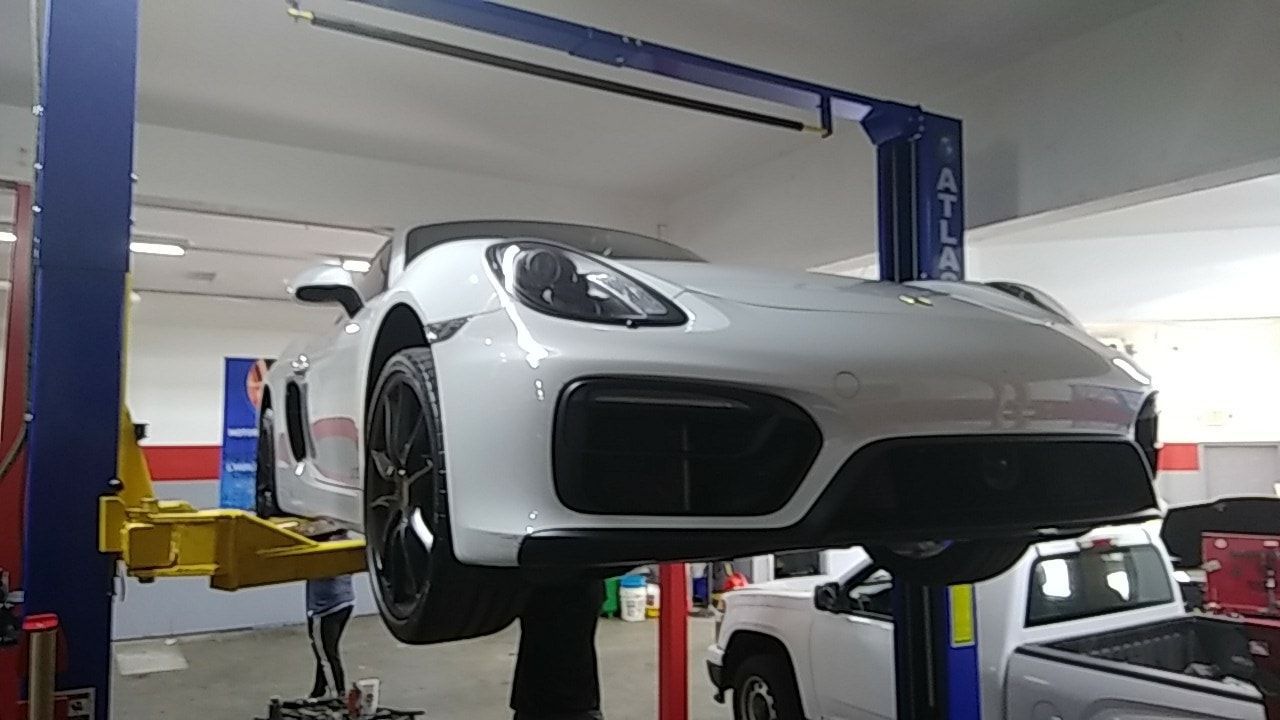 A white sports car is sitting on top of a lift in a garage.