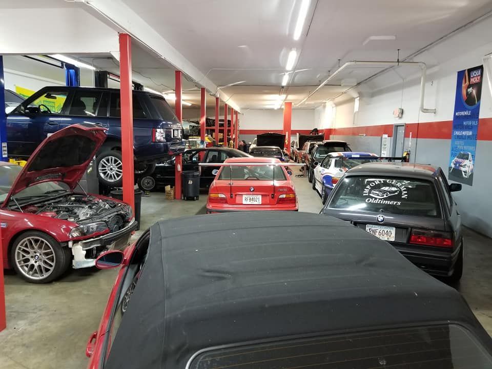 A row of cars are parked in a garage with the hoods up