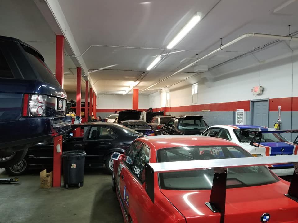 A red bmw is parked in a garage with other cars
