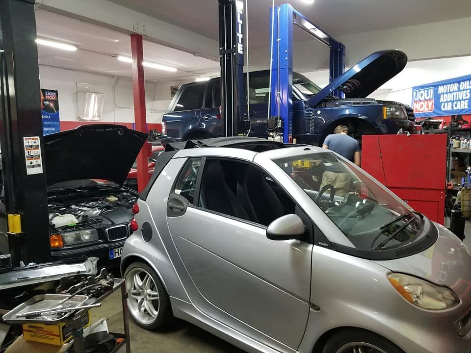 A smart car is sitting on a lift in a garage.