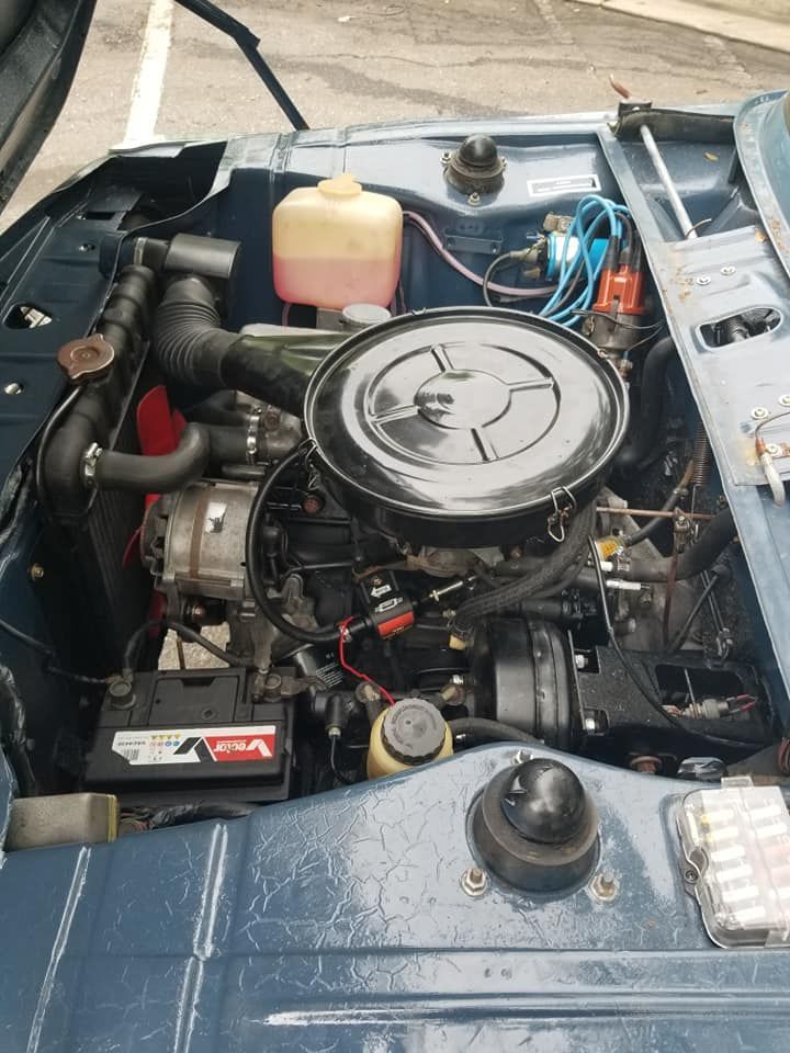 The engine of a blue car is shown with the hood open.