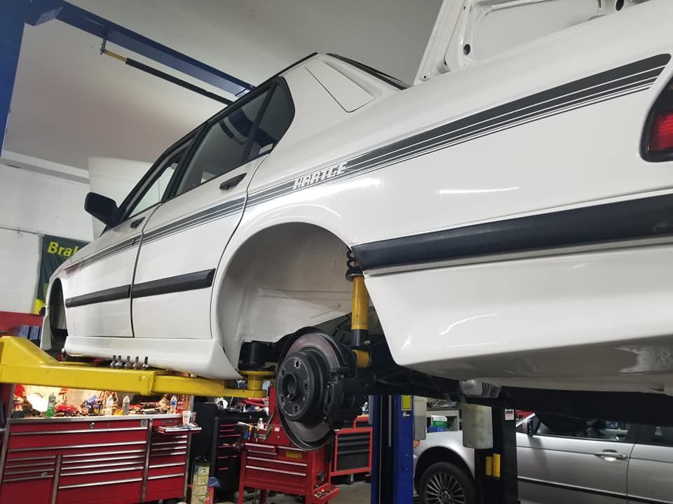 A white car is sitting on a lift in a garage.