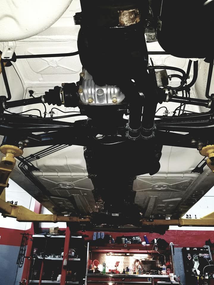 The underside of a car is shown in a garage