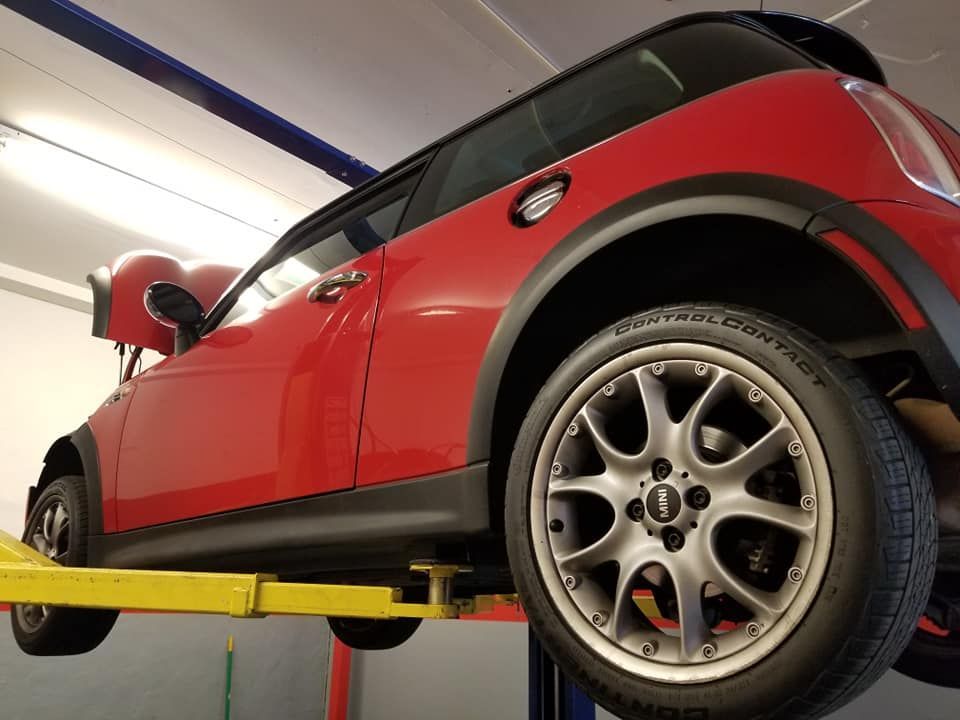 A red mini cooper is on a lift in a garage.