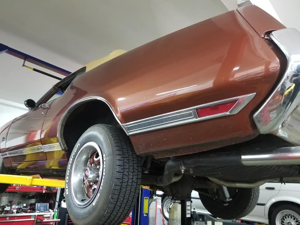 A brown car is sitting on a lift in a garage
