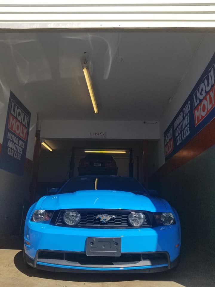 A blue mustang is parked in a garage