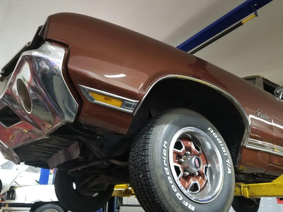 A brown car is on a lift with a tire that says bfgoodrich