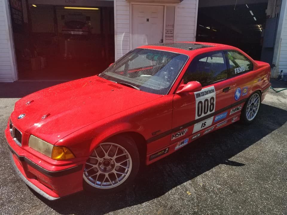 A red bmw is parked in front of a garage.